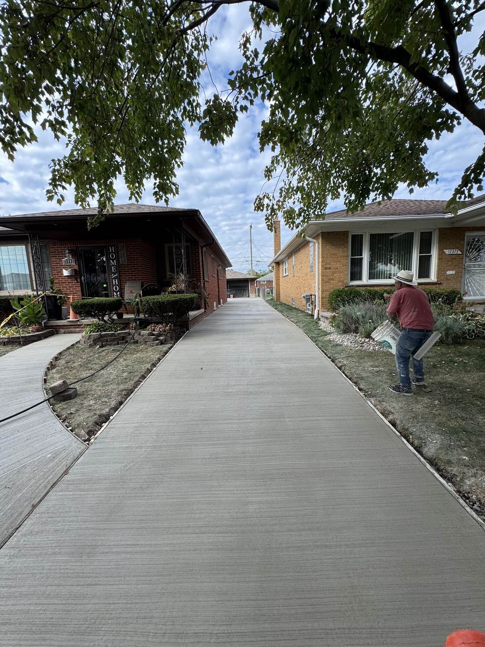 A finished broom-finish driveway curing between two brick houses